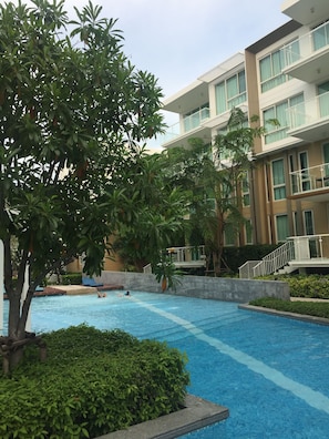 A swimming pool surrounded by lush greenery and modern buildings.