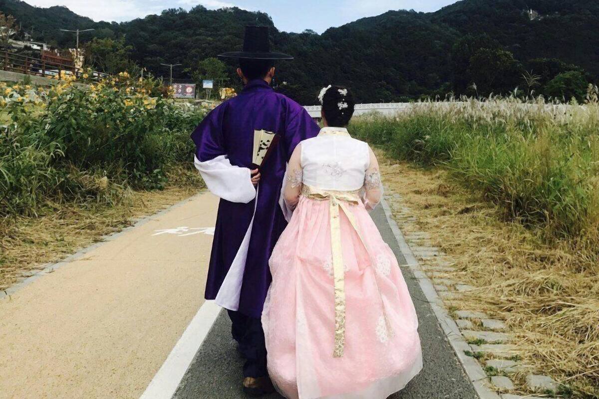 A pathway with a person in traditional attire and a woman in a pink dress walking away.