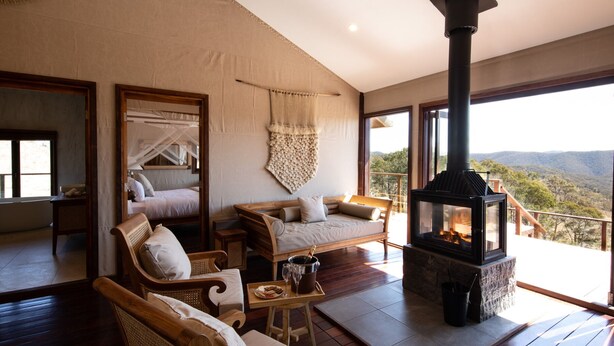 Una habitación acogedora con chimenea, asientos cómodos y un amplio ventanal con vistas panorámicas.