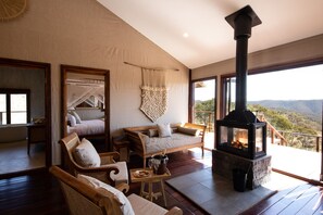 Une pièce chaleureuse avec une cheminée, des fauteuils confortables et une grande fenêtre donnant sur un paysage magnifique.