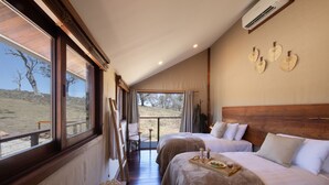 Un dormitorio con dos camas, cabecera de madera, ventana con vistas al exterior y una mesita con bandeja.