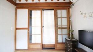 A traditional Japanese room with sliding doors, a TV, and a small plant on a cabinet. - Sori poonggyung (Jeonju)