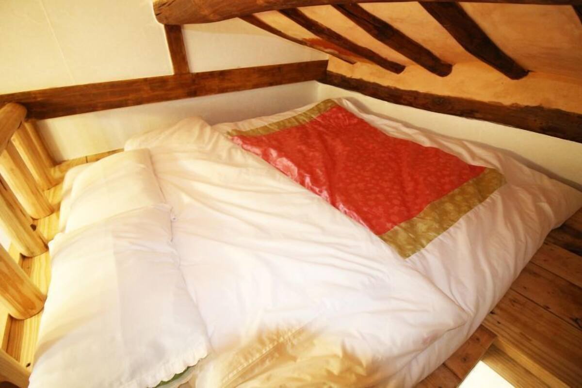 Un lit en bois recouvert d’une couverture blanche et rouge.