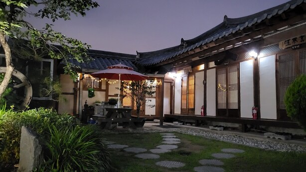 A traditional Japanese-style building with a covered outdoor seating area, stone pathways, and a small garden. - Sori poonggyung (Jeonju)