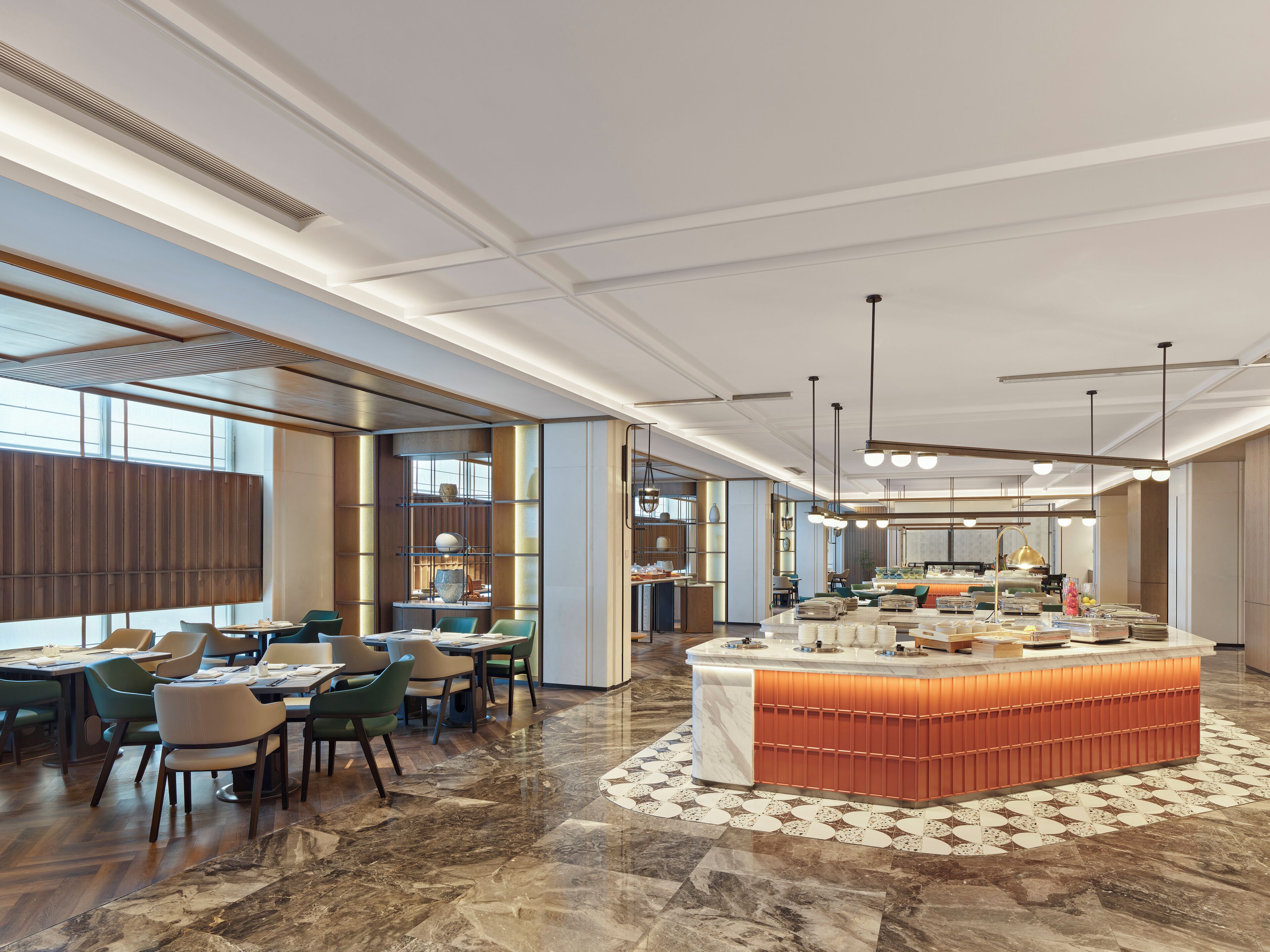 A spacious hotel lobby with a central island, dining area with chairs, and a large window providing natural light.