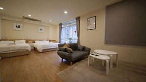 Ein Hotelzimmer mit zwei Einzelbetten, einem Schlafsofa, einem kleinen Tisch und einem Fenster mit Vorhängen.
