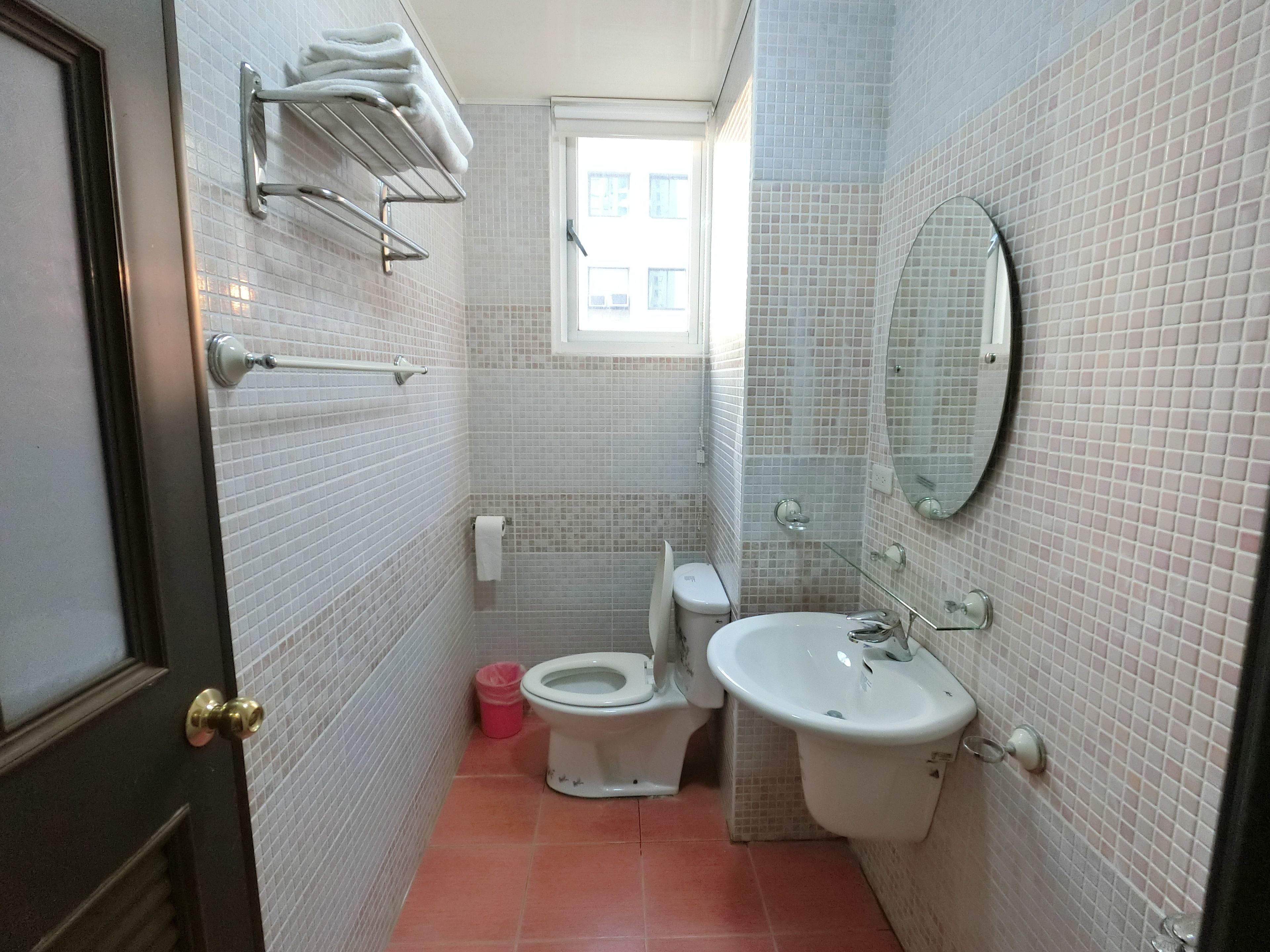 A small bathroom with a toilet, sink, and a window.