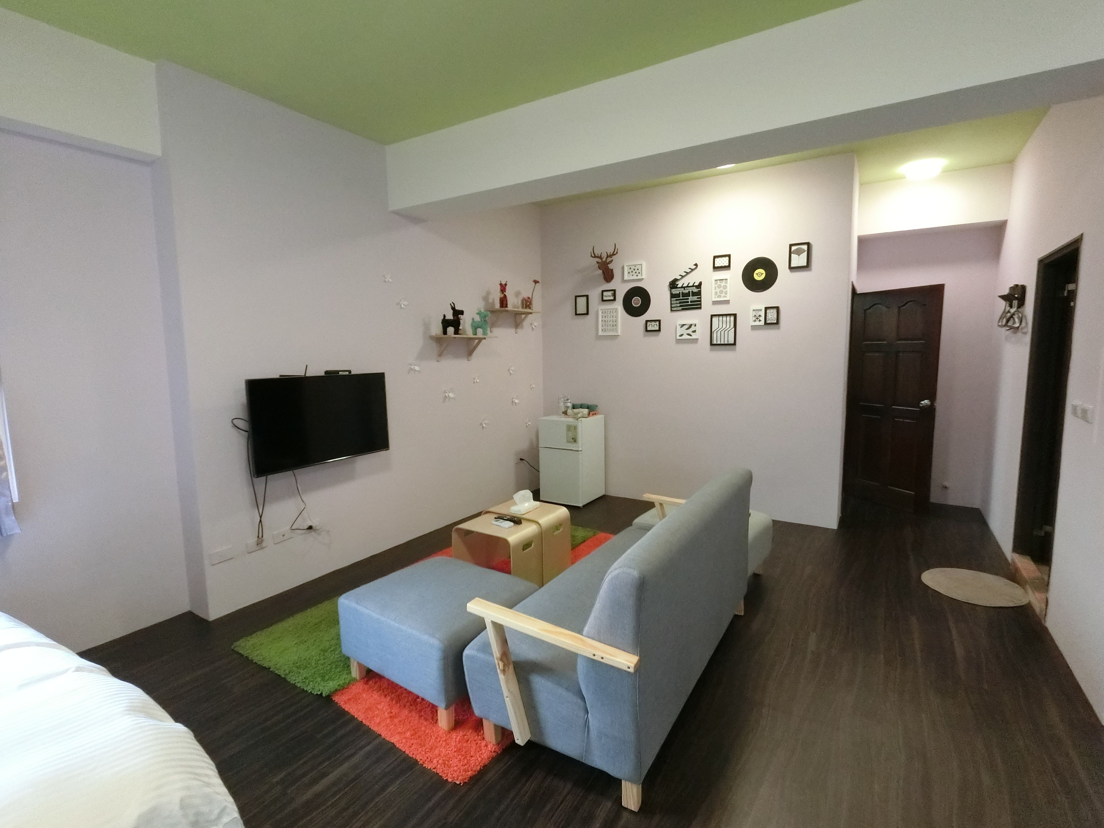 A compact living space with a sofa, a television, a small table, and a refrigerator.