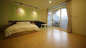 Ein Hotelzimmer mit Bett, kleinem Tisch, Sofa und Balkon mit Blick.