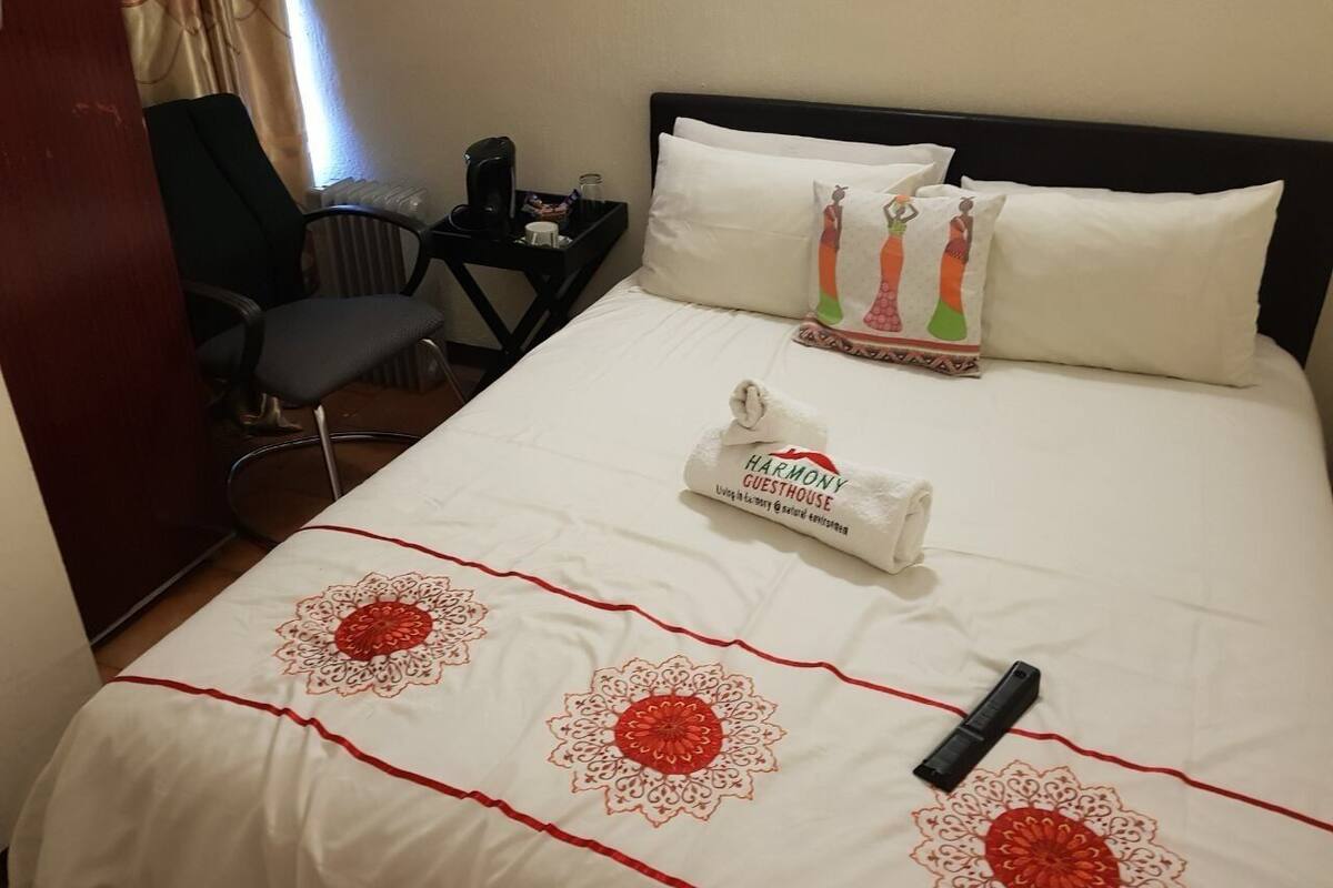 A hotel room with a bed, a nightstand, a chair, and a window with curtains.