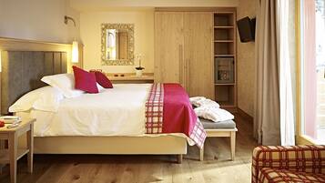 A hotel room with a large bed, bedside tables, a wardrobe, a television, and a window with curtains.