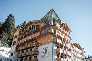 Ett hotell med flera våningar, träbalkonger och en skidbacke i bakgrunden.