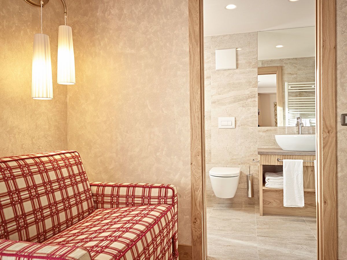 A bathroom with a red and white checkered sofa, a white sink, and a mirror above the sink.