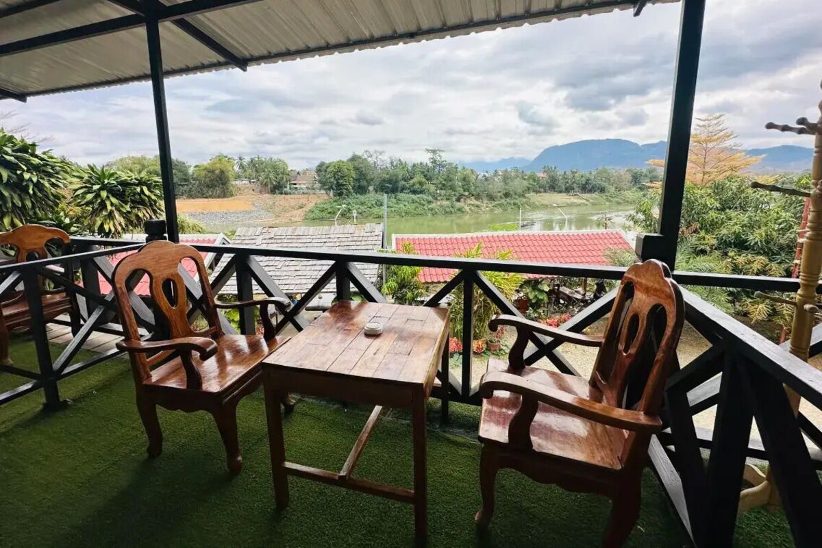Un espacio de estar al aire libre cubierto con una mesa y sillas, con vistas a un paisaje con vegetación y montañas a lo lejos.