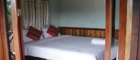 Een slaapkamer met een houten bedframe, witte beddengoed en twee rode kussens.