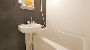 A bathroom with a white sink, a mirror, and a shower. There are toiletries on a shelf above the sink. - Apartment Sun Bright (Tokyo)