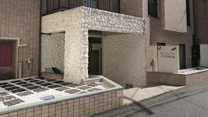 A building with a stone facade, a balcony, and a tiled entrance. - Apartment Sun Bright (Tokyo)