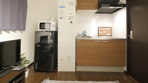 A compact kitchen with a microwave, refrigerator, and sink. - Apartment Sun Bright (Tokyo)