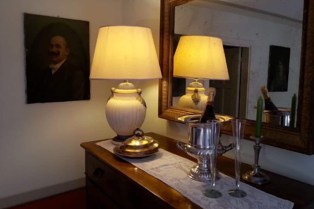 Una habitación con un aparador de madera, dos lámparas de mesa, un espejo y un retrato enmarcado en la pared.