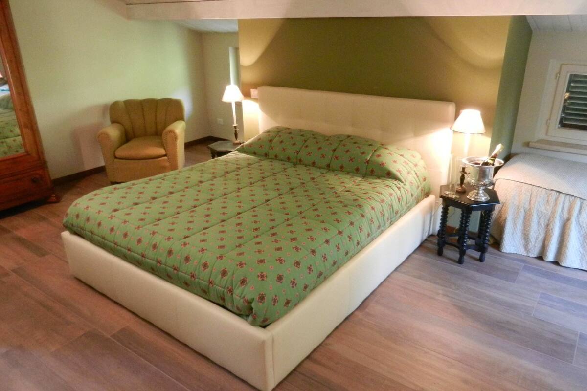 Un dormitorio con cama, una silla, una mesita de noche y una lámpara.