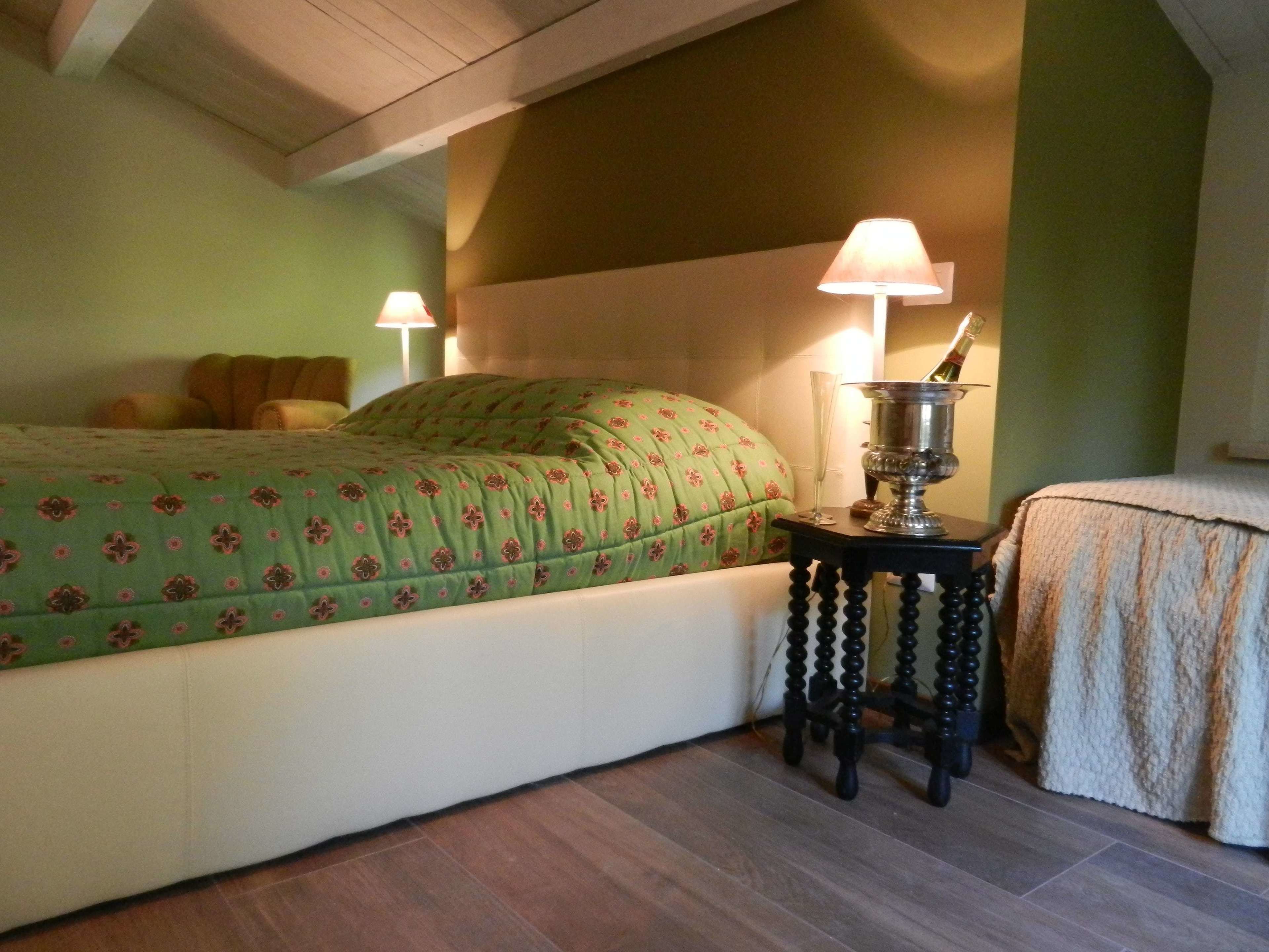 Une chambre à coucher avec un lit, deux lampes de chevet, une petite table avec une lampe et un objet décoratif posé sur la table.
