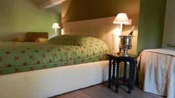 Une chambre à coucher avec un lit, deux lampes de chevet, une petite table avec une lampe et un objet décoratif posé sur la table.