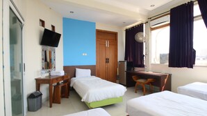 A hotel room with two single beds, a desk with a chair, a television mounted on the wall, and a window with curtains. - Hotel Vala Malioboro Yogyakarta (Yogyakarta)