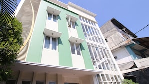 A multi-story building with a green and white facade, large windows, and a visible entrance. - Hotel Vala Malioboro Yogyakarta (Yogyakarta)