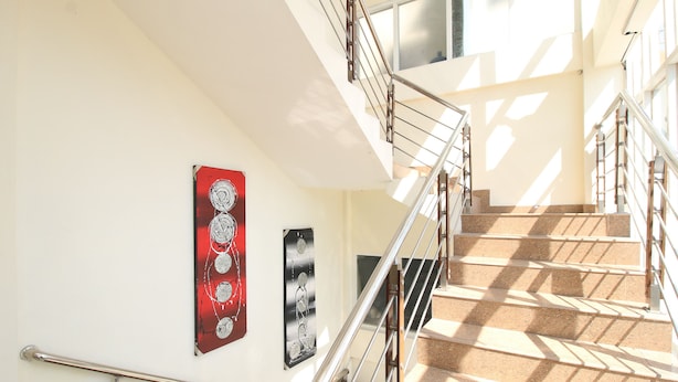 A staircase with metal railings and artwork on the walls. - Hotel Vala Malioboro Yogyakarta (Yogyakarta)