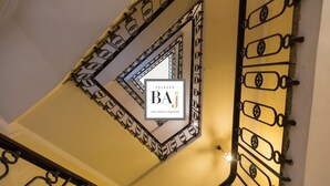 Un escalier orné de rampes en métal ouvragé et une enseigne indiquant une maison d’hôtes dans le quartier de Trastevere.