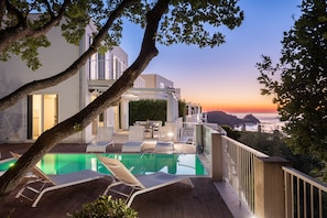A modern outdoor pool area with lounge chairs, a dining table, and a view of the ocean at sunset. - Villas d'Orlando - with private pool and sea view (Capo d'Orlando)