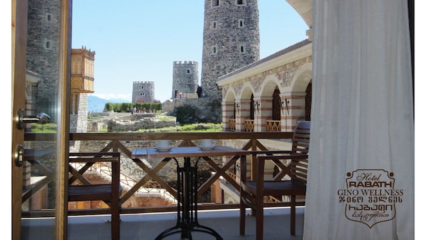 A balcony with a view of ancient stone towers and a building with arches. - Gino Wellness Rabath Hotel and Spa (Akhaltsikhe)