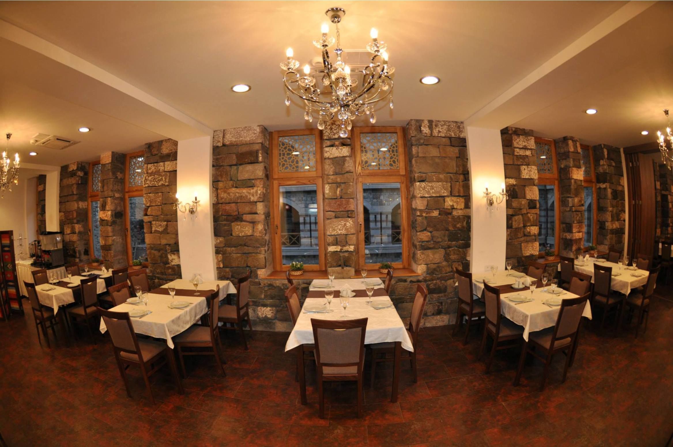 Un restaurante con paredes de piedra, varias mesas y candelabros.