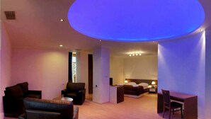 A modern hotel room with a large circular skylight, a cozy seating area with sofas, a bed, and a dining table. - Gino Wellness Rabath Hotel and Spa (Akhaltsikhe)