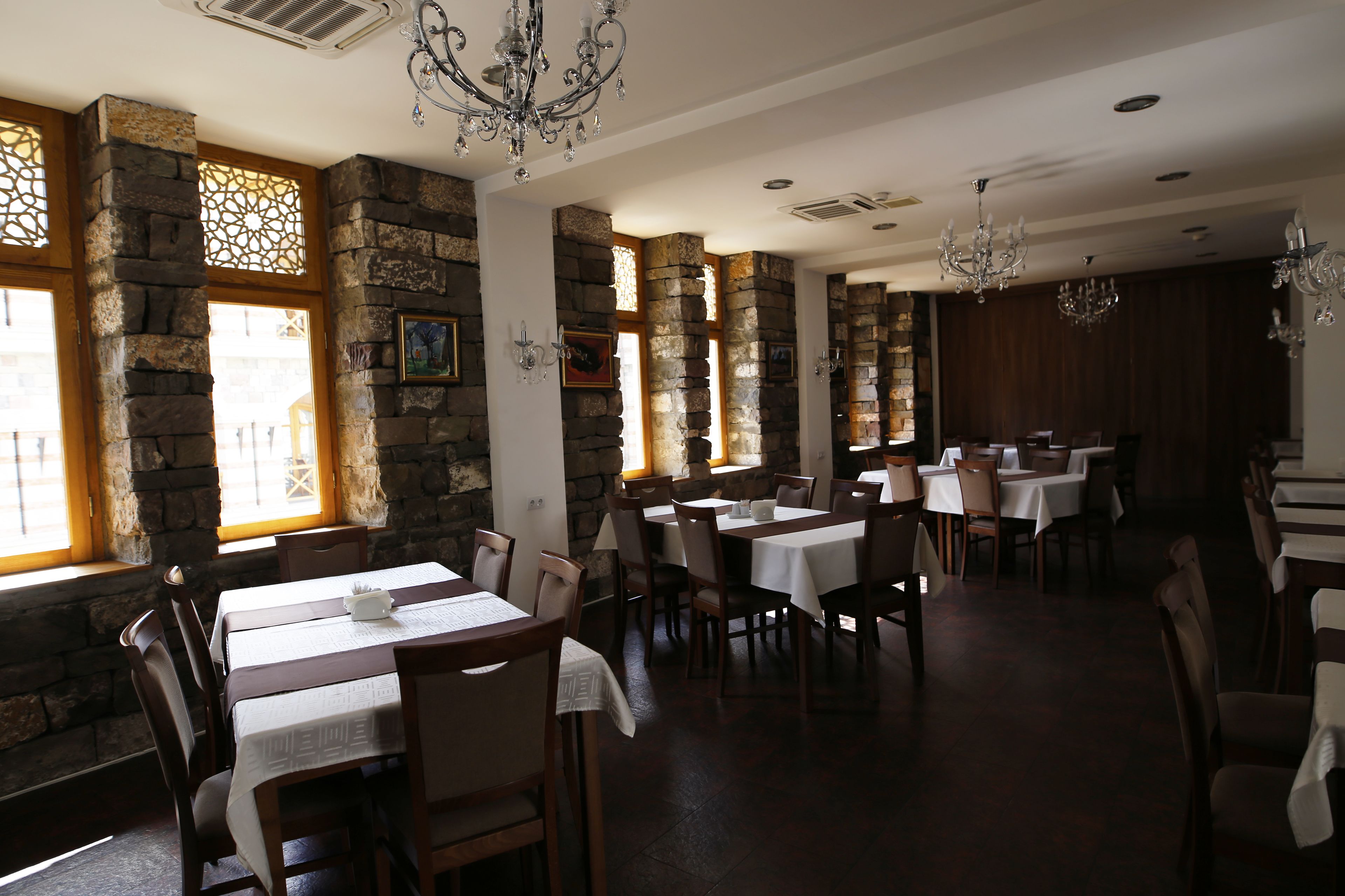 Een restaurant met stenen muren, houten tafels en stoelen.