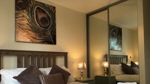 Quarto de hotel com uma cama grande, duas luminárias de cabeceira, um espelho e um quadro na parede.