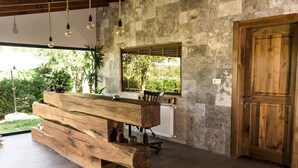 A rustic wooden bench with a rustic table, a window with a view of greenery, and a wooden door. - Cevizdibi Otel (Kartepe)