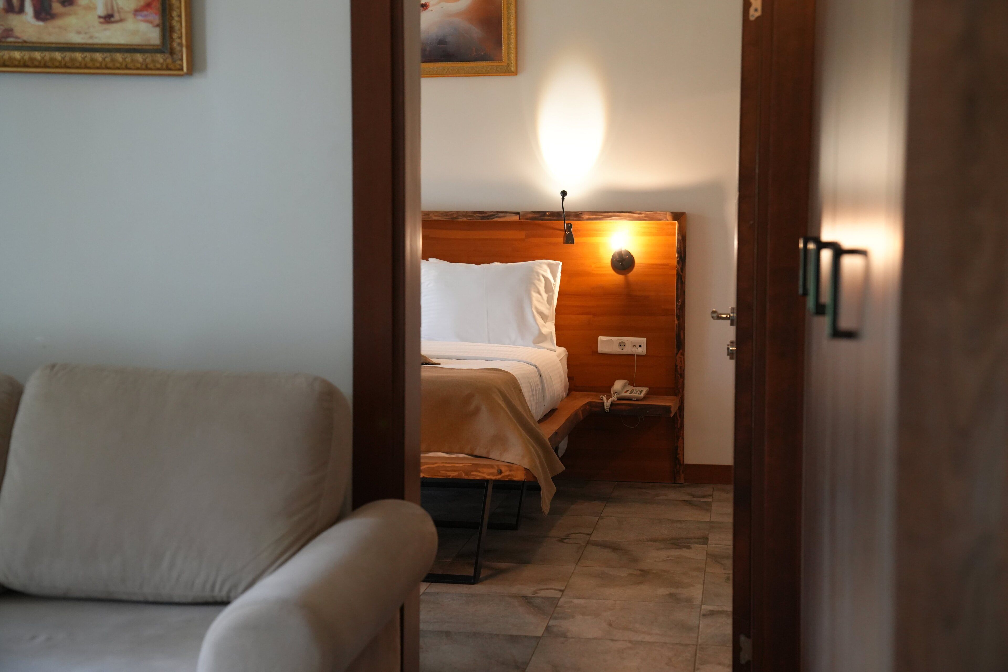 Una habitación de hotel con una cama, una mesita de noche con lámpara, un teléfono y un sofá.