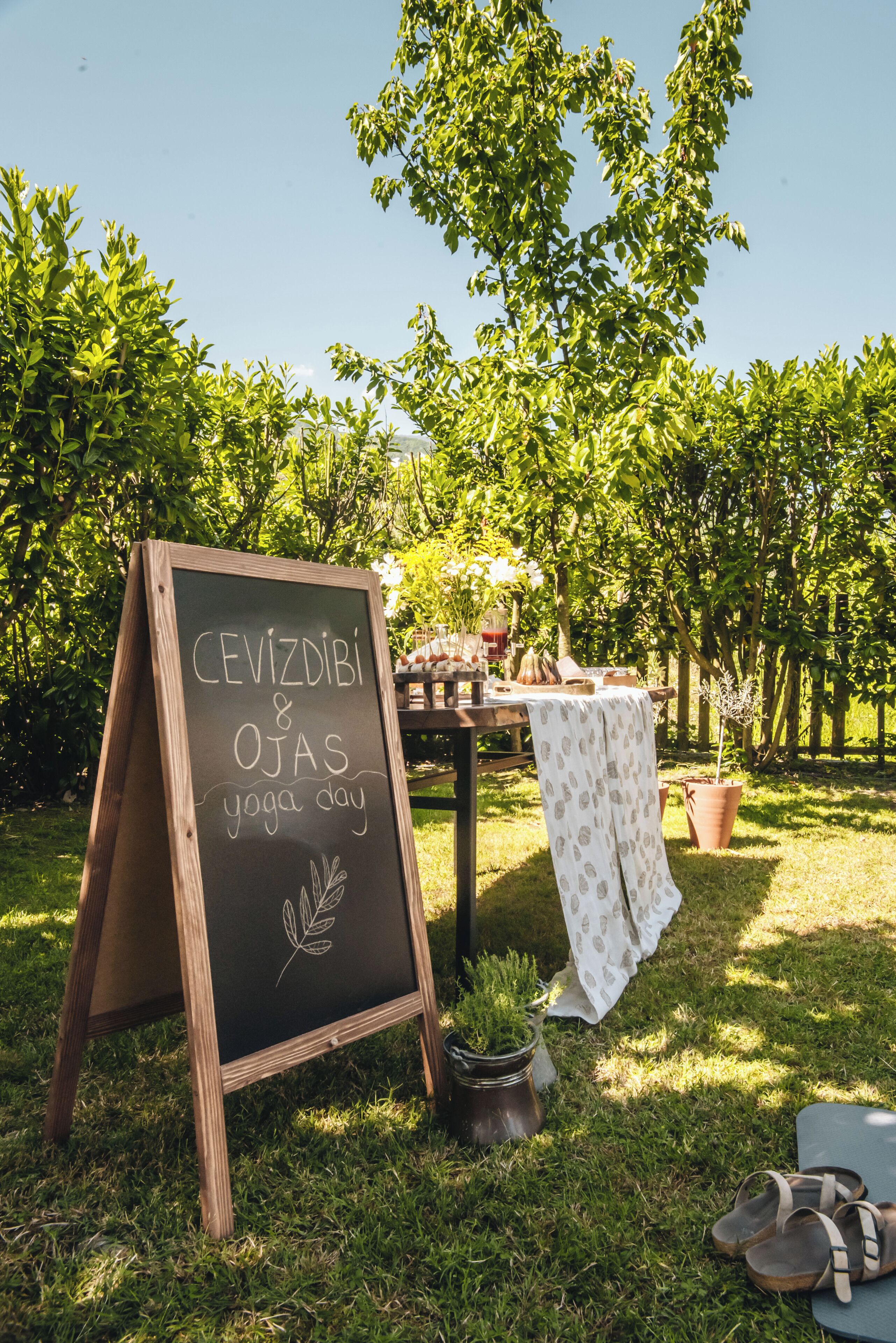 Una lavagna con scritto un evento di yoga in un giardino.