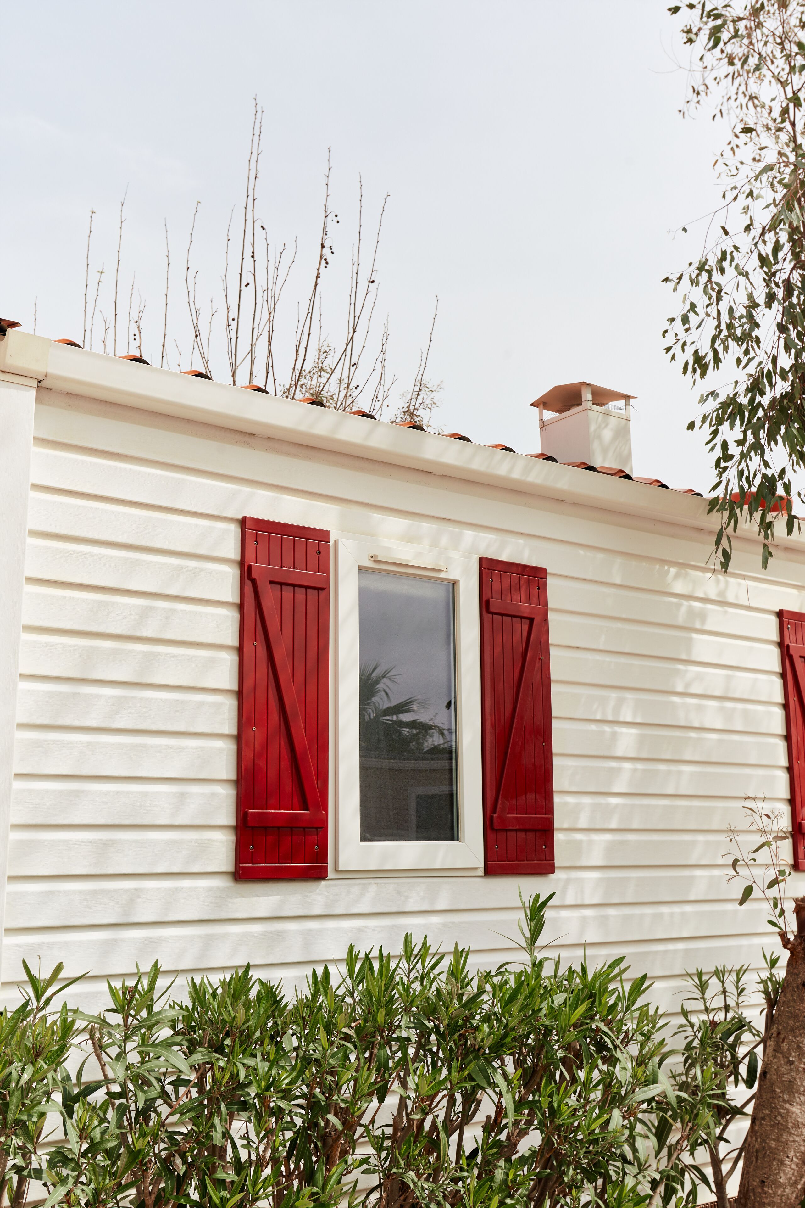 A white building with red shutters and a window.