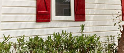 A white building with red shutters and a window.