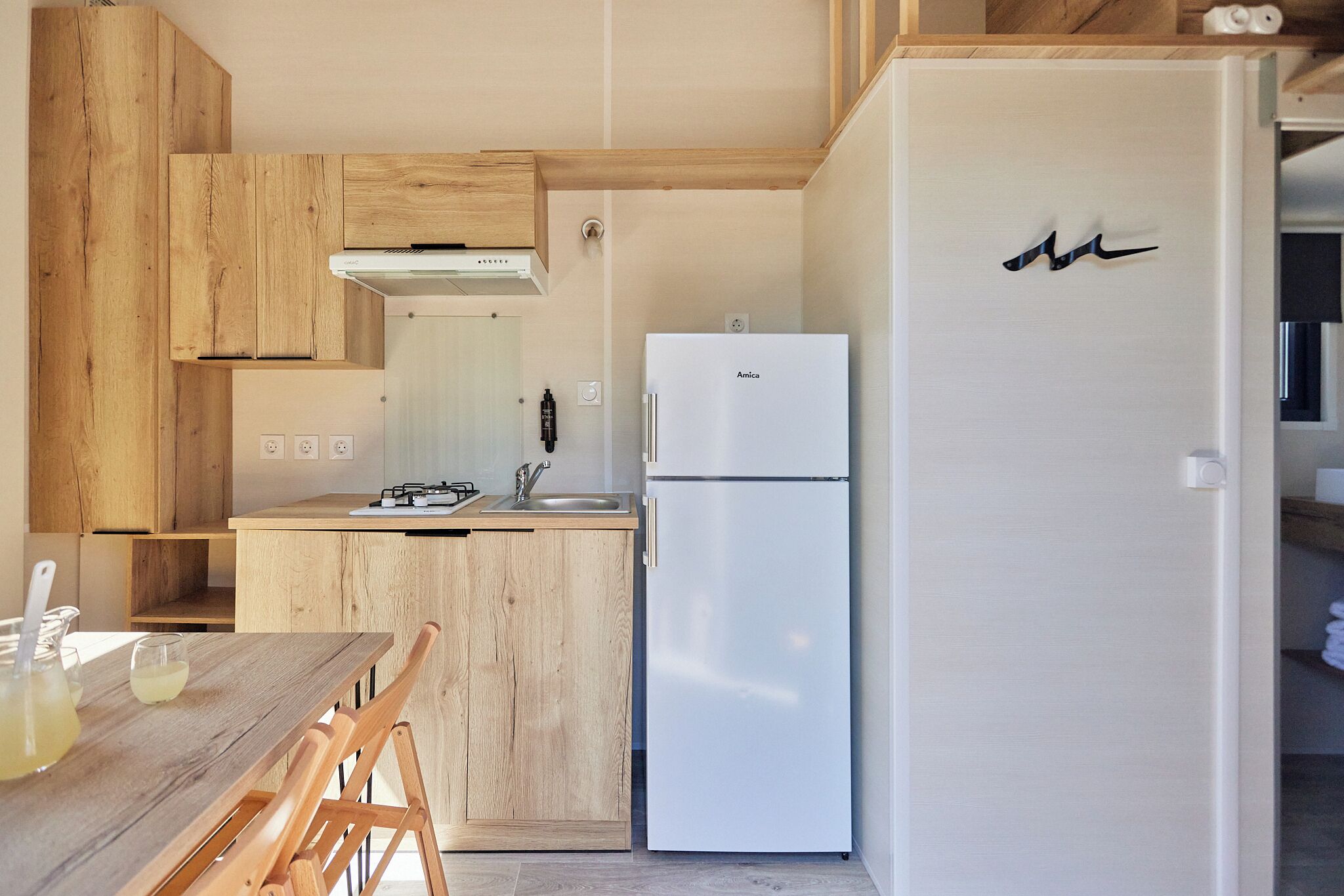 Eine kleine Küche mit Holzschränken, einem weißen Kühlschrank und einer Arbeitsplatte mit Spüle.