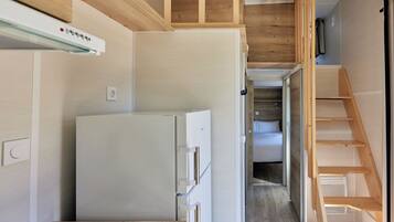 Una cocina compacta con refrigerador integrado, muebles de madera y un lavamanos pequeño.