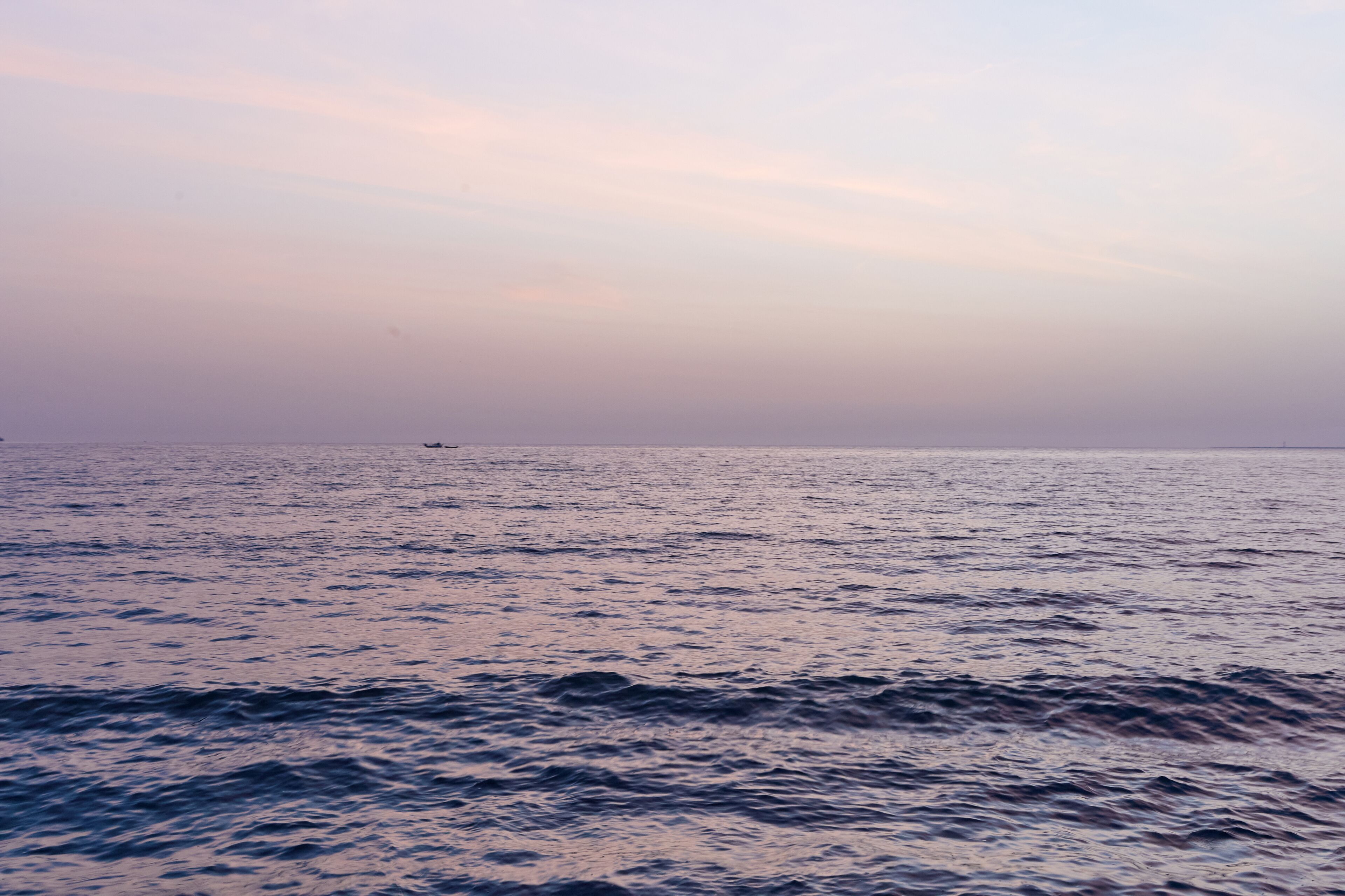 A calm sea with gentle waves and a distant boat.
