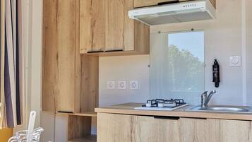 Een moderne keuken met houten keukenkastjes, een roestvrijstalen spoelbak en een eethoek met een houten tafel en stoelen.