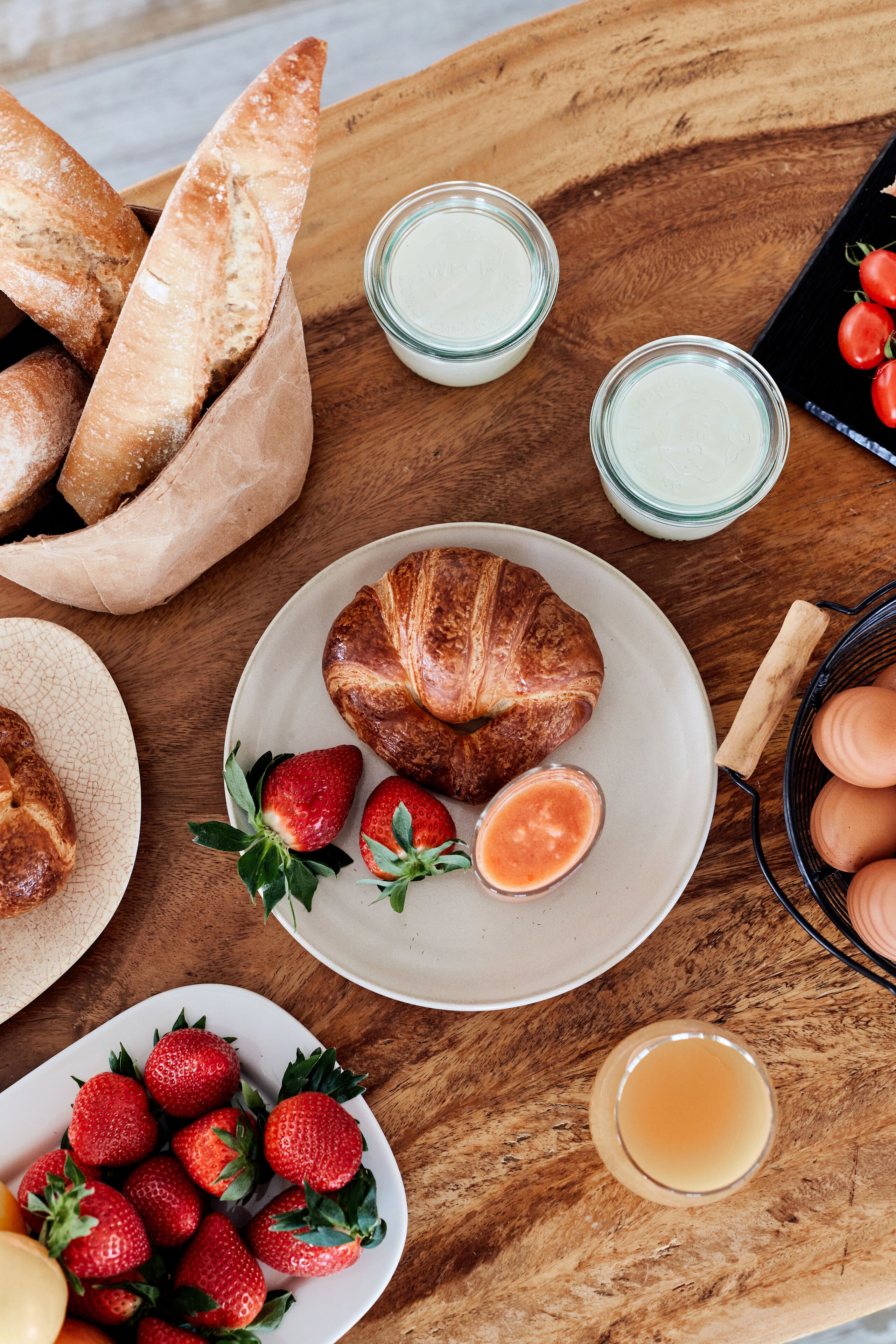 Een houten tafel met brood, aardbeien en honing.