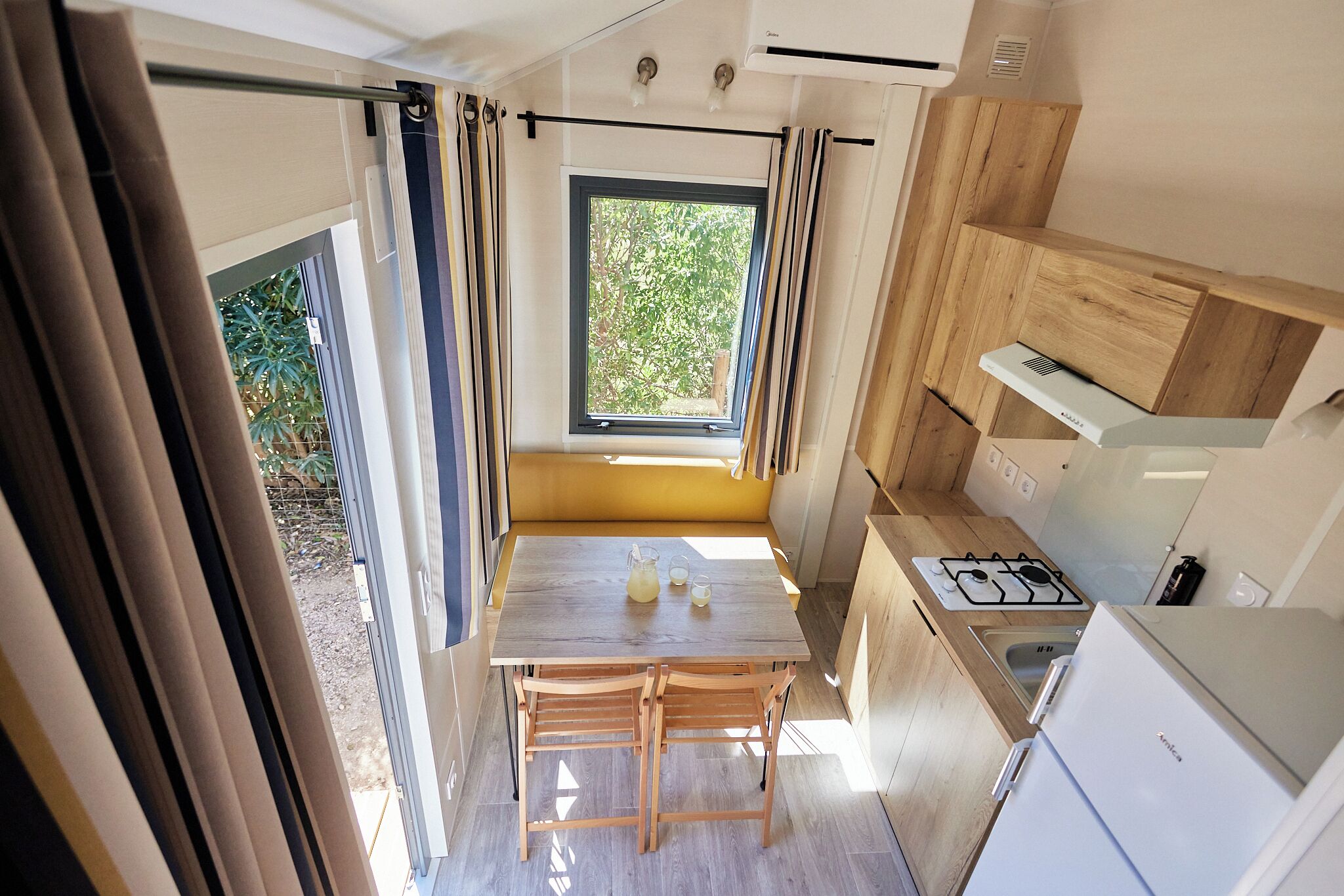 Une cuisine de taille réduite avec une table en bois, une cuisinière à gaz et un réfrigérateur.