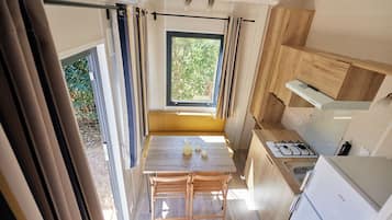 Una cocina compacta con una mesa de madera, una estufa a gas y un refrigerador.