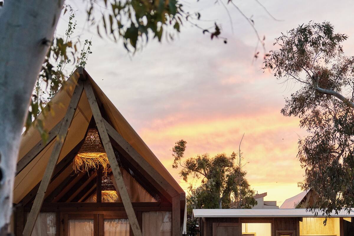 Eine Holzhütte mit einem Strohdach, einer kleinen Veranda und Kiesböden.