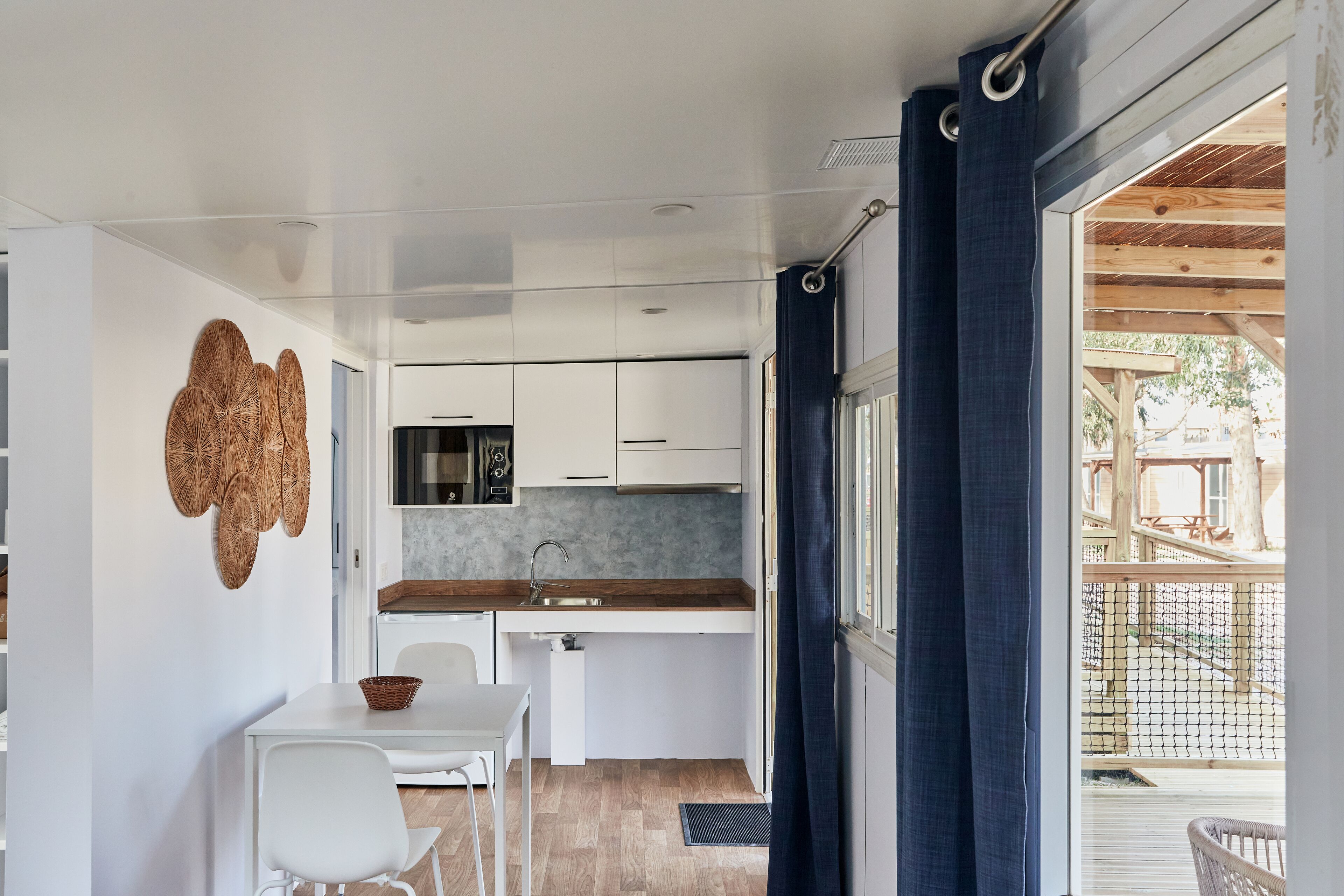 A compact kitchen with white cabinets, a wooden countertop, and a dining area with a white table and chairs.